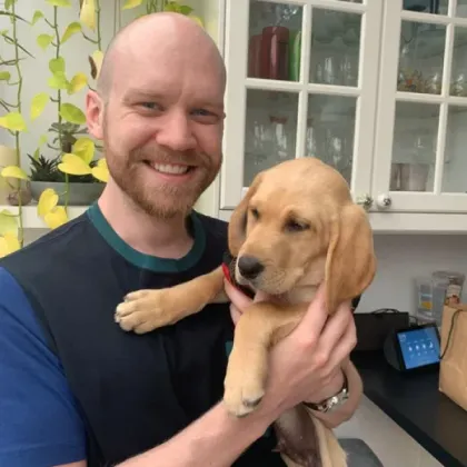 Steve holding a golden retriever puppy