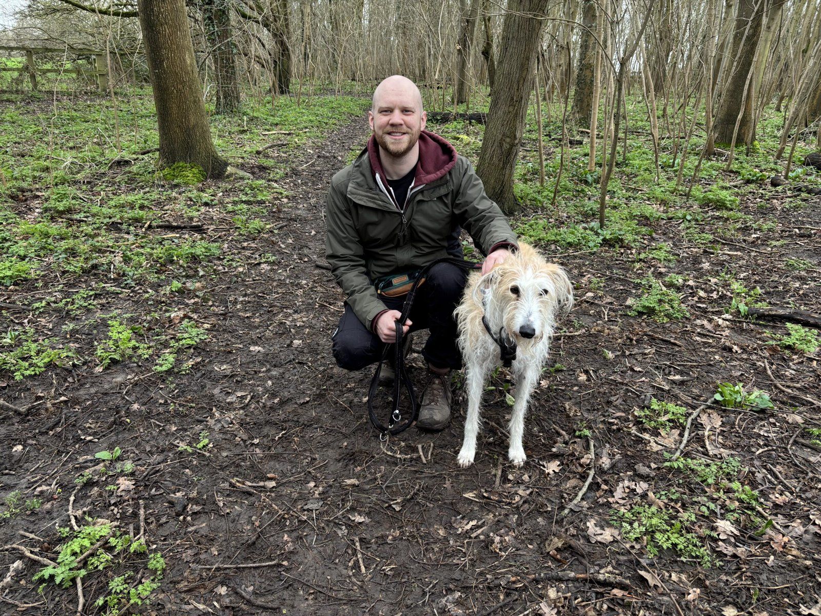 Steve crouching in the woods with a white dog
